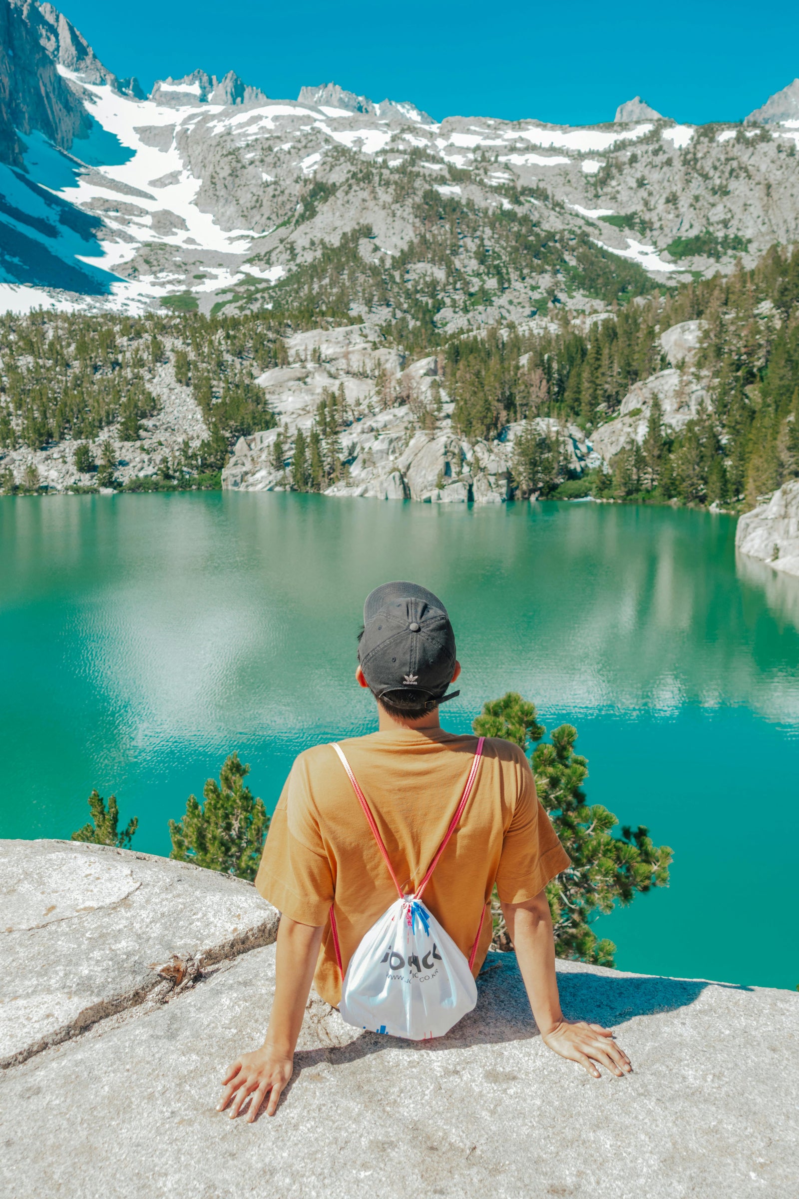 person relaxing in front of a mountain lake