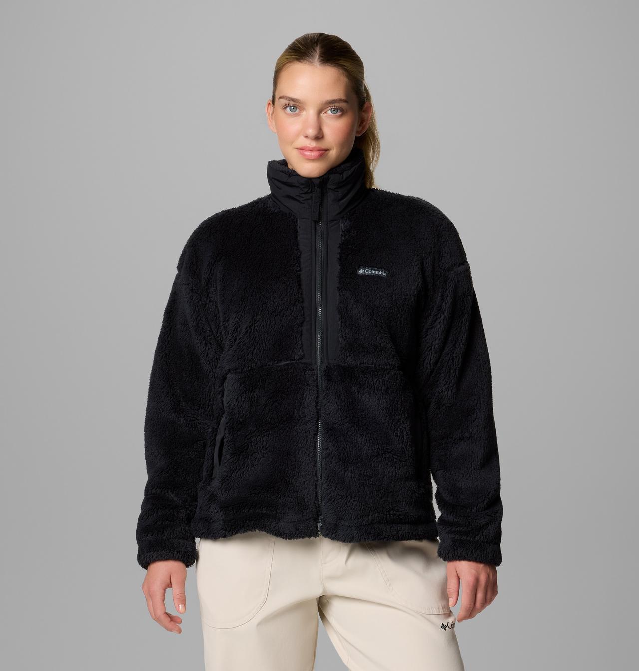 Woman wearing a black fleece jacket with a visible Columbia logo on a gray background