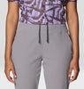 Person wearing a patterned shirt and gray pants on a plain background