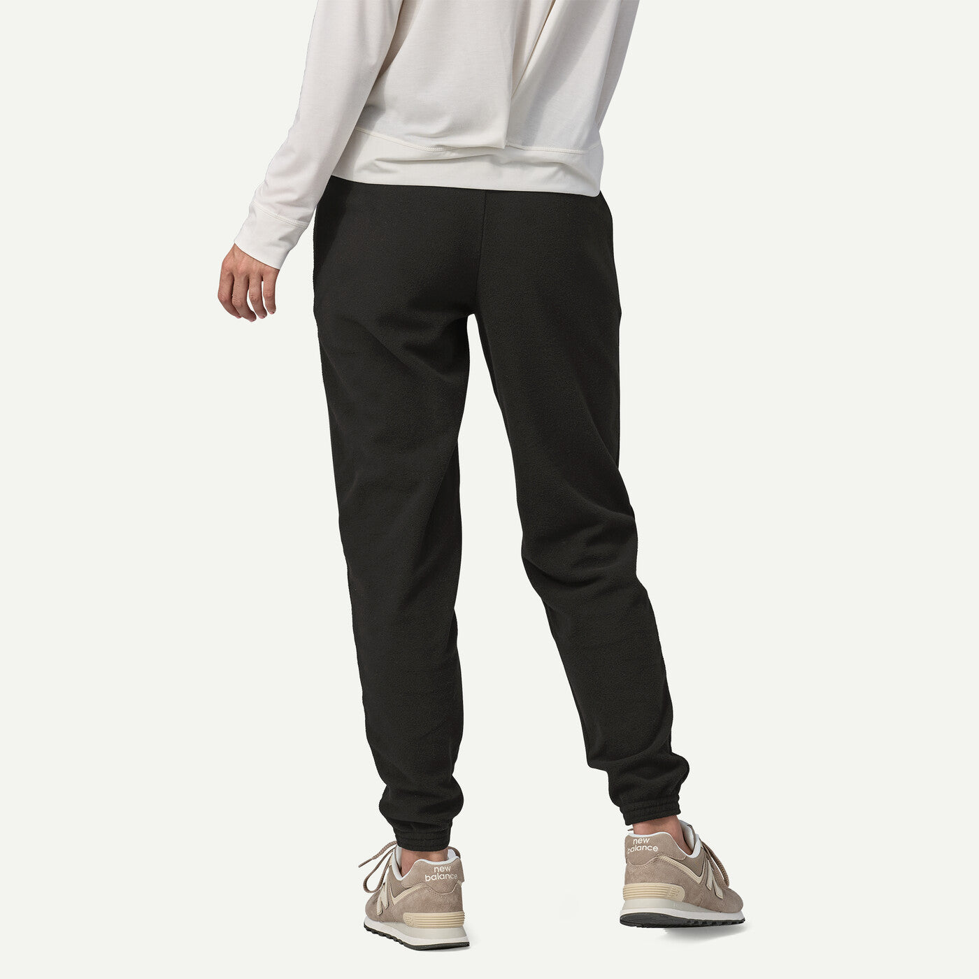 Person wearing black jogger pants and a white sweatshirt on a white background