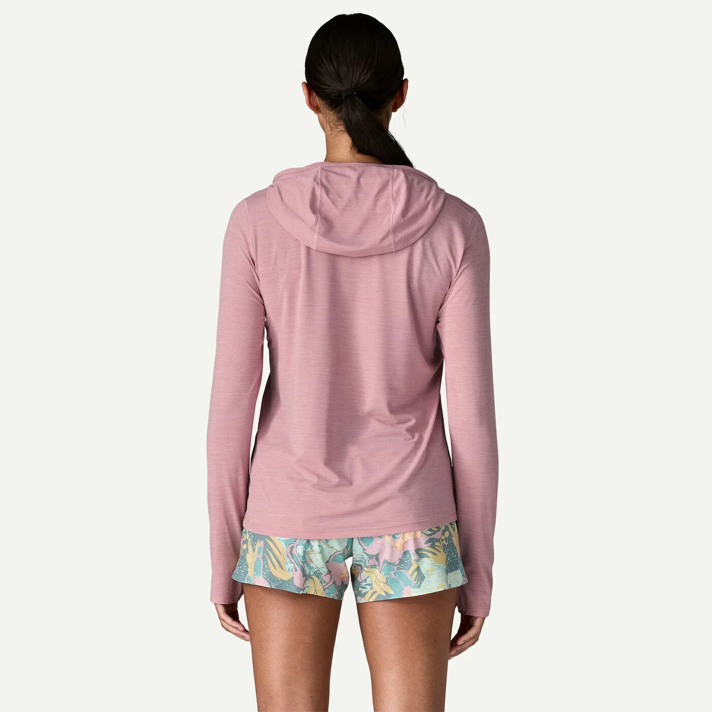 Person wearing a pink hoodie and floral shorts on a white background