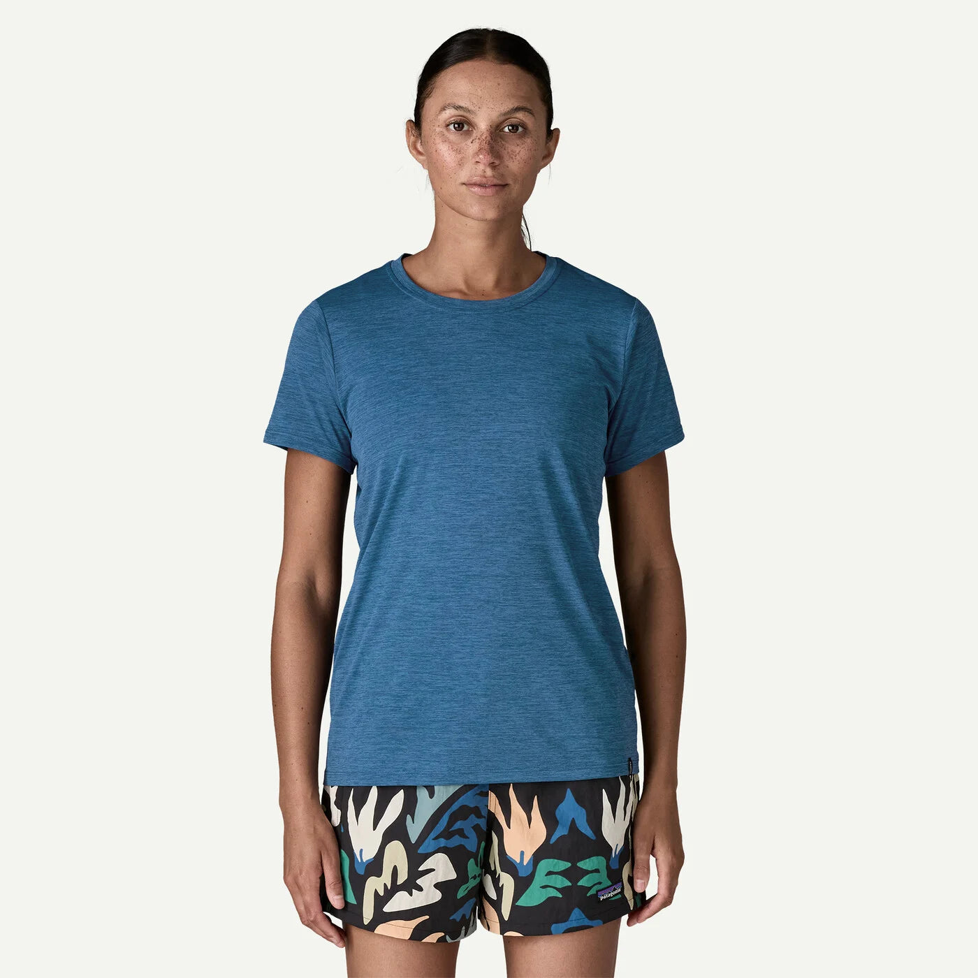 Woman wearing a blue t-shirt and patterned shorts on a white background