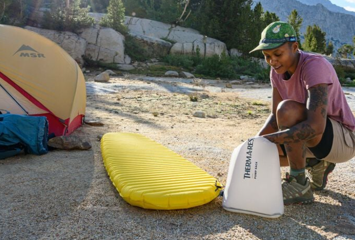 the thermarest neo air xlite nxt sleeping pad shown being blown up by a model