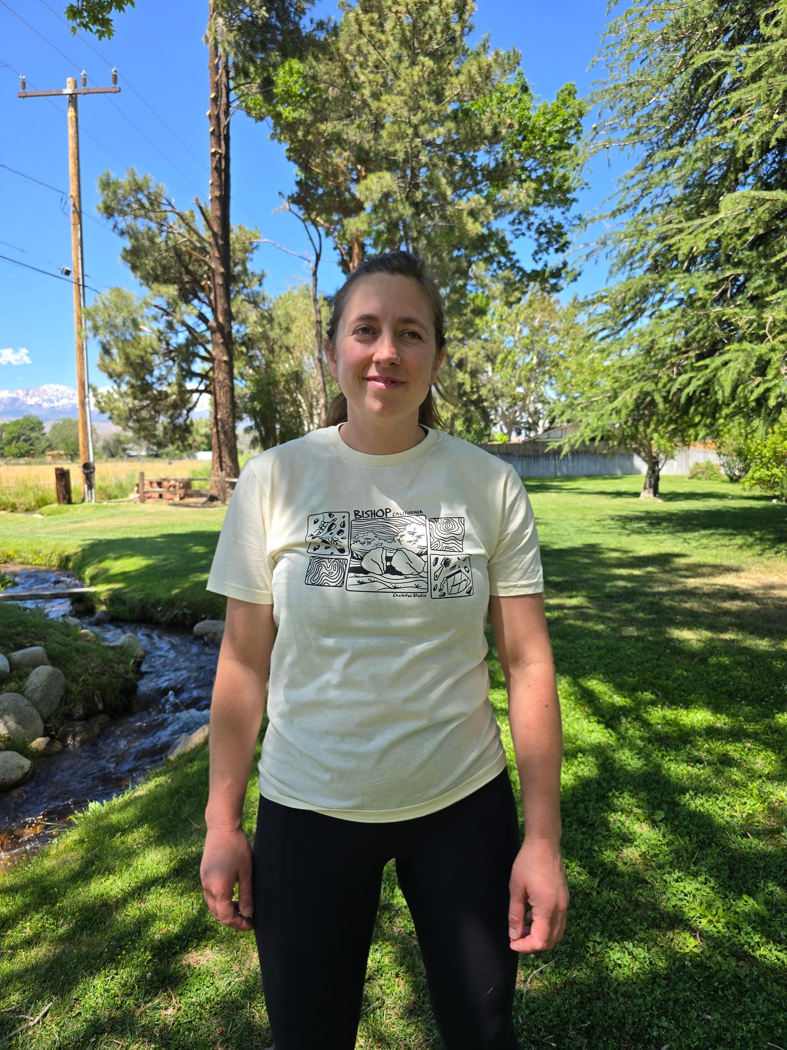 Person wearing a white t-shirt with graphics in a park setting