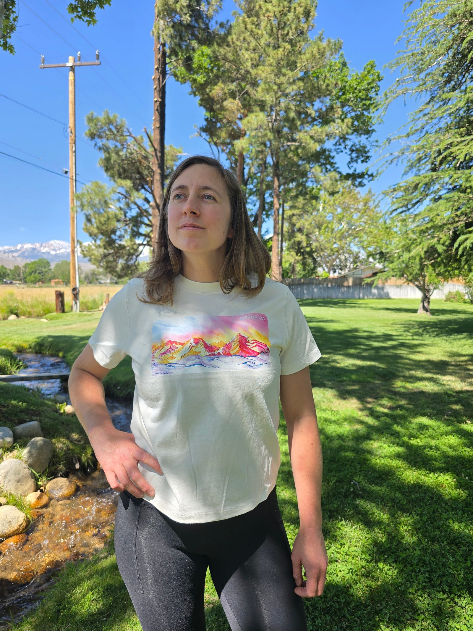 white women's t-shirt with colorful mountain graphic, worn by the artist