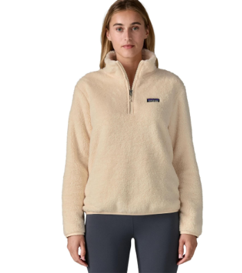 A woman modeling a Patagonia quarter-zip fleece pullover in a light cream color, paired with dark gray leggings, against a plain white background.