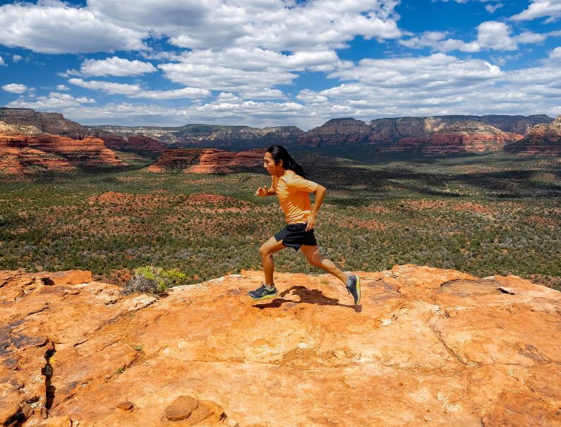 a photo of the topo mountain racer 3 mens shoe in the color black/lime, view of a model wearing the shoe while running in the desert