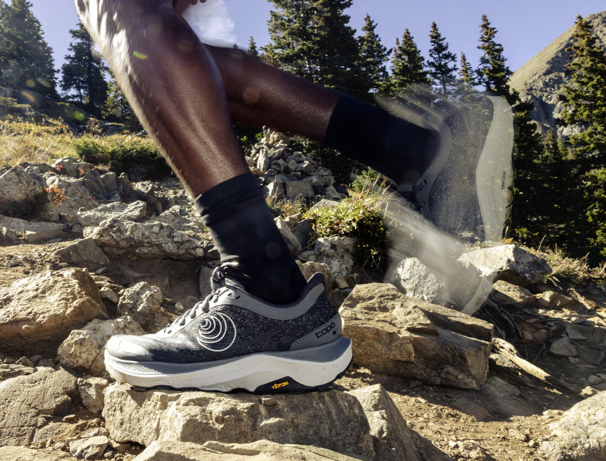 the topo ultraventure 4 running shoe in grey color, a model running in them