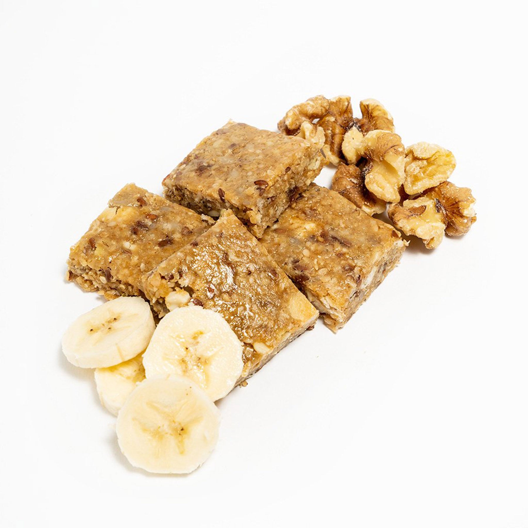 four square slices of the banana nut bread probar some bananas and nuts strewn about