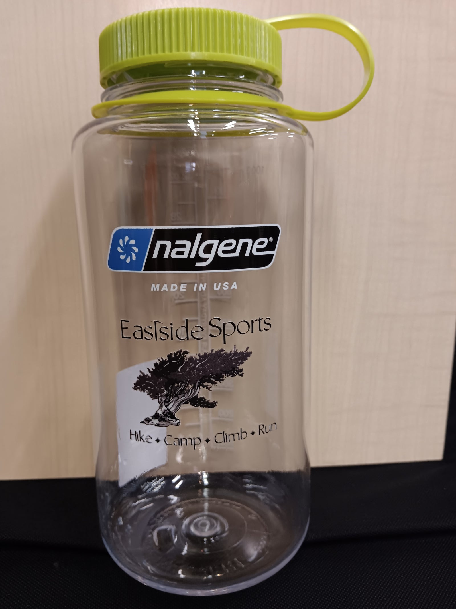 A clear plastic water bottle with a lime green cap and carrying loop, featuring a printed label for 'nalgene' and 'Eastside Sports'.