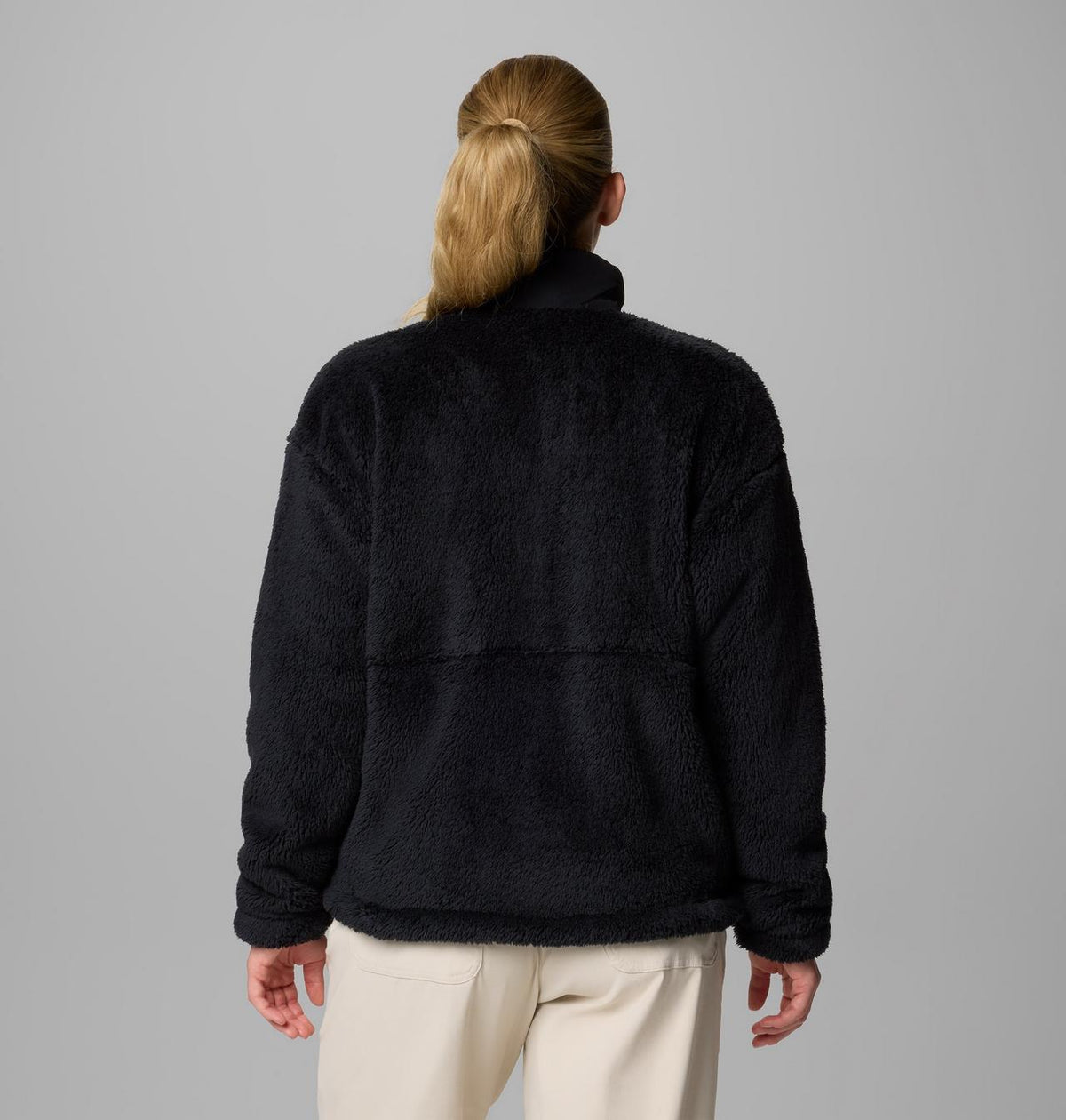 Person seen from back, wearing a black fleece jacket on a gray background