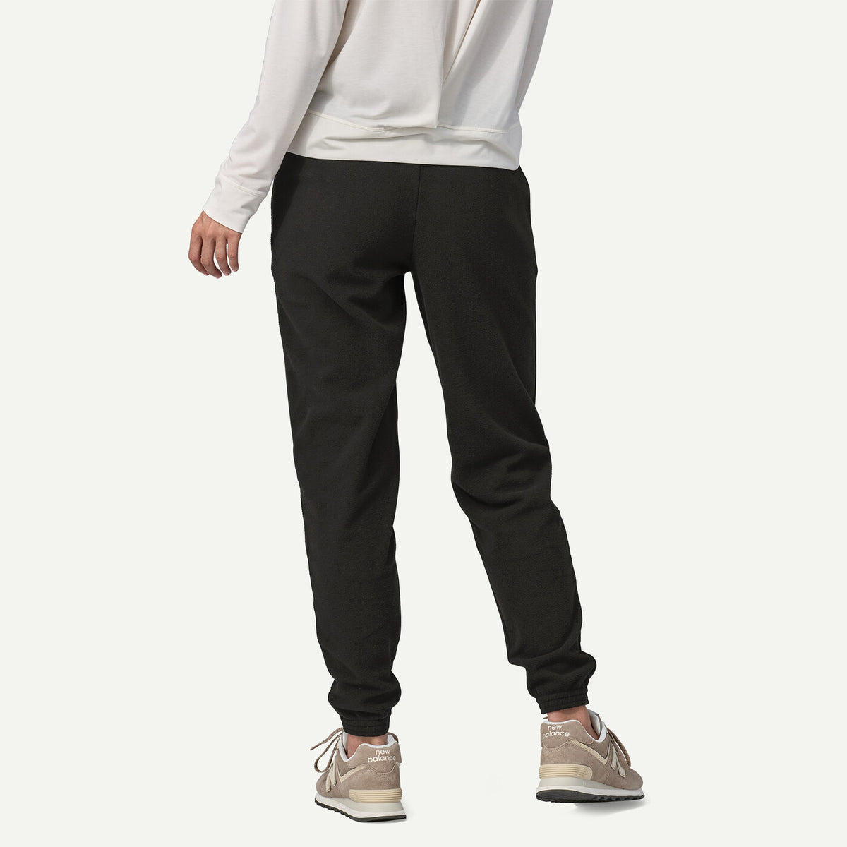 Person wearing black jogger pants and a white sweatshirt on a white background
