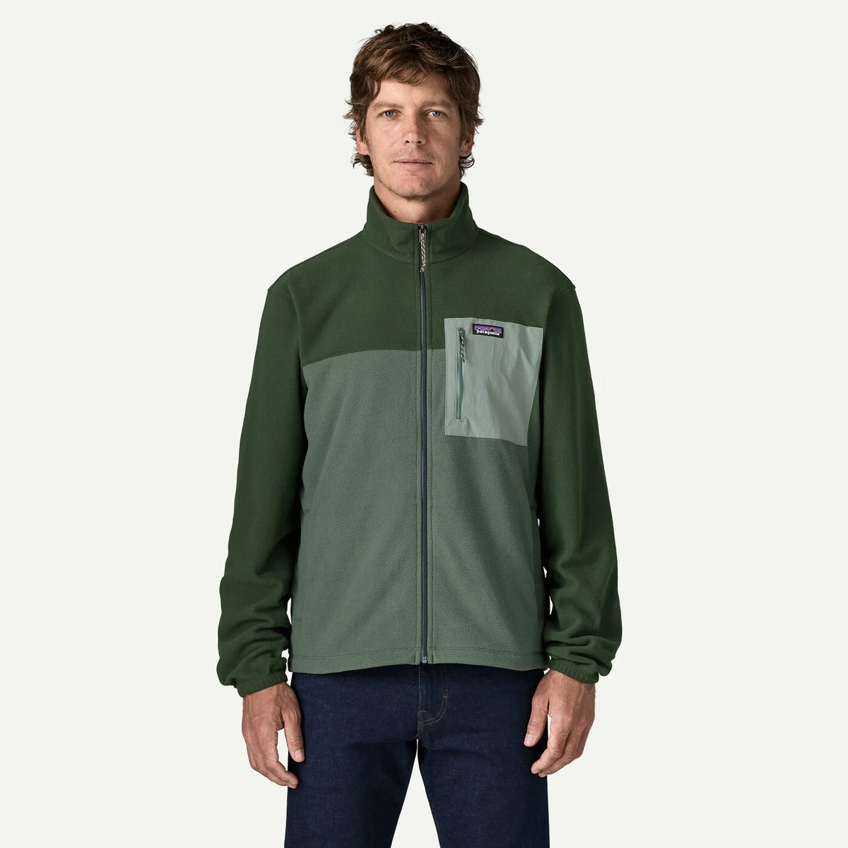 Man wearing a green jacket with a visible brand logo on a white background
