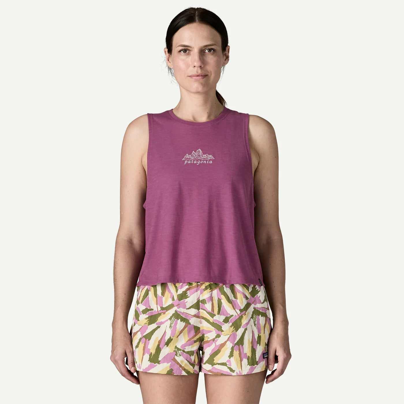 Woman wearing a purple tank top and patterned shorts on a white background
