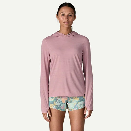Woman wearing a pink long-sleeve hoodie and patterned shorts on a white background