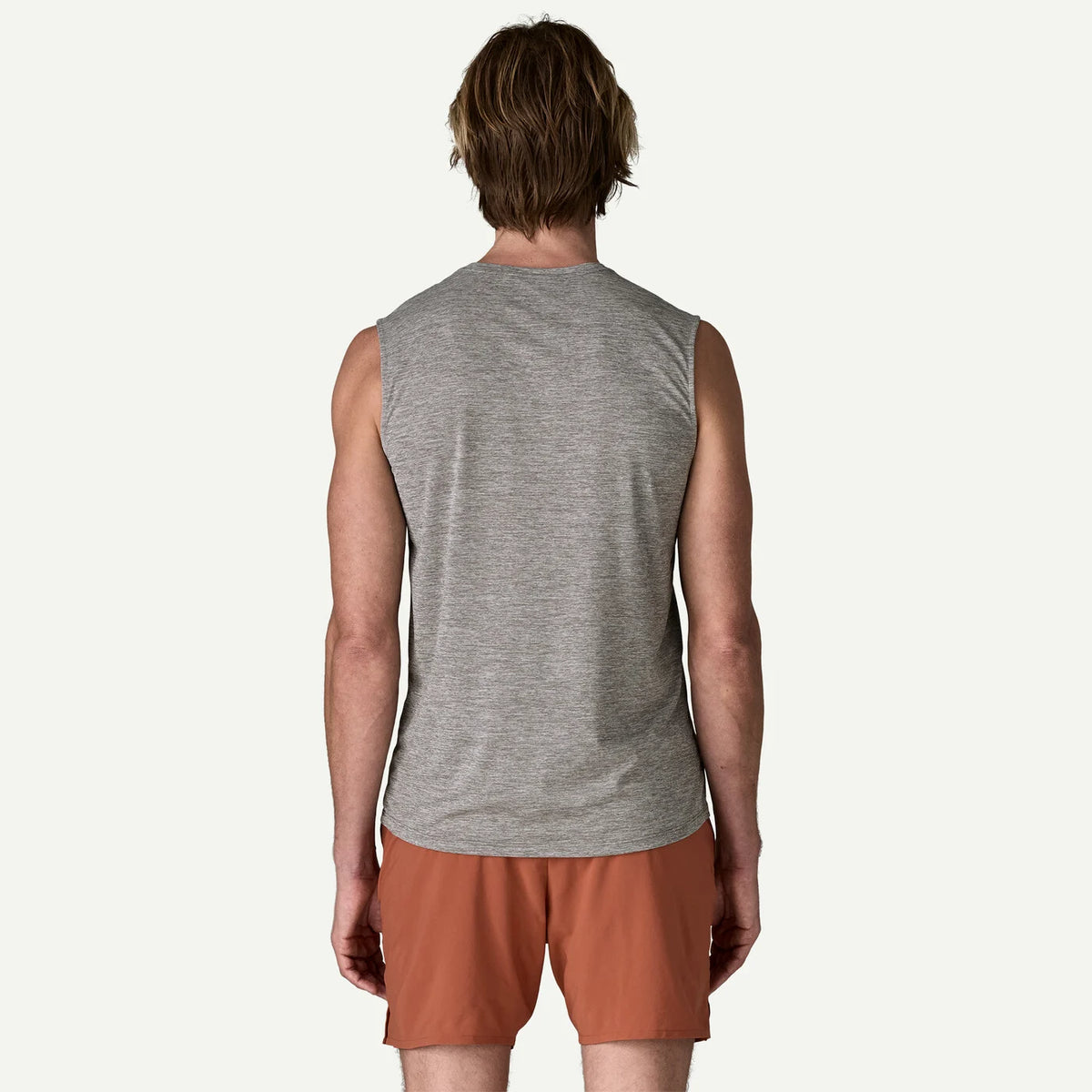 Person wearing a gray sleeveless shirt and brown shorts on a white background