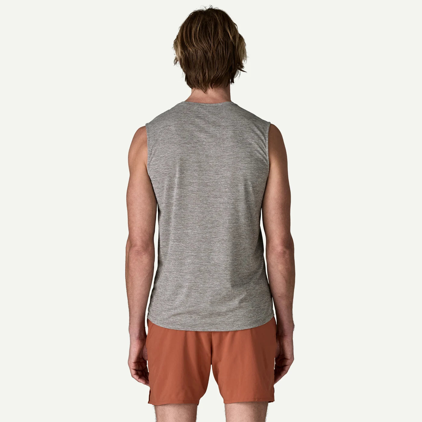 Person wearing a gray sleeveless shirt and brown shorts on a white background