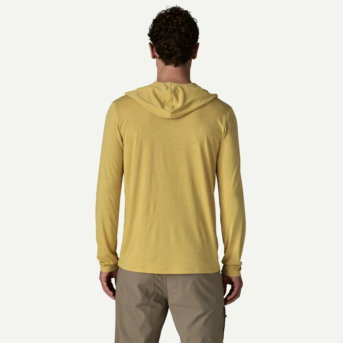 Person wearing a yellow hoodie and beige pants on a white background