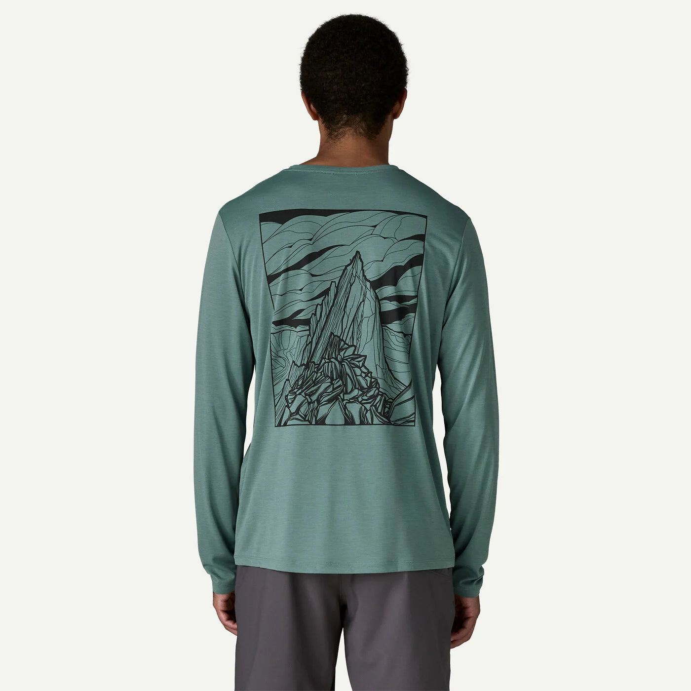 Person wearing a teal long-sleeve shirt with a mountain graphic on the back against a white background