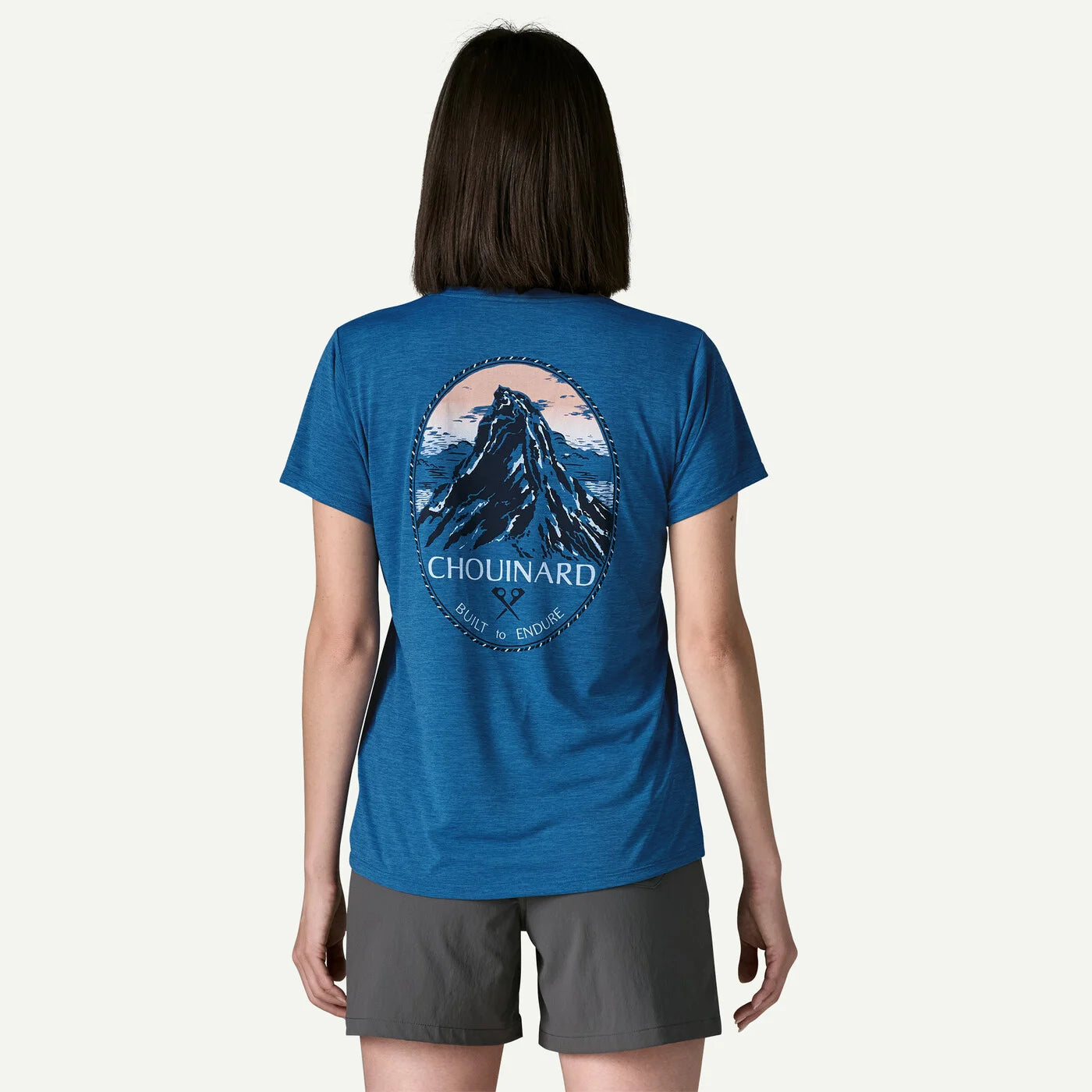 Person wearing a blue t-shirt with a mountain graphic and 'Chouinard' branding on the back.