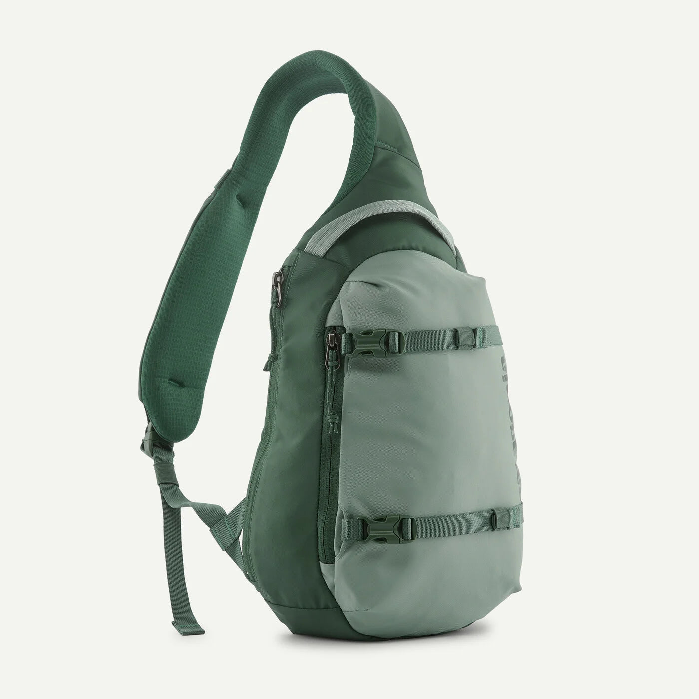 A green sling backpack shown from a side profile view against a light off-white background.