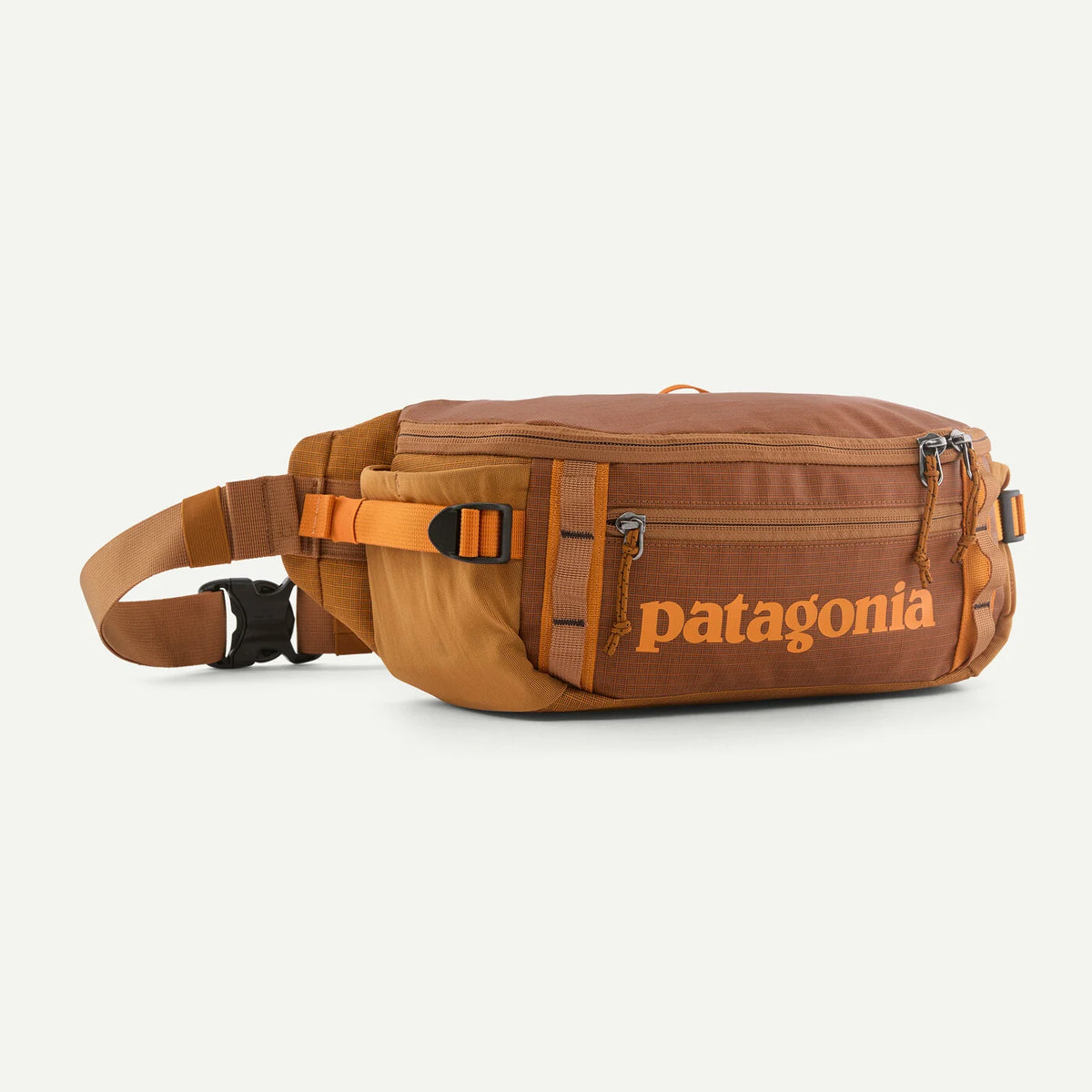 A brown Patagonia hip pack with an orange logo and orange-brown webbing straps, shown on a light off-white background.