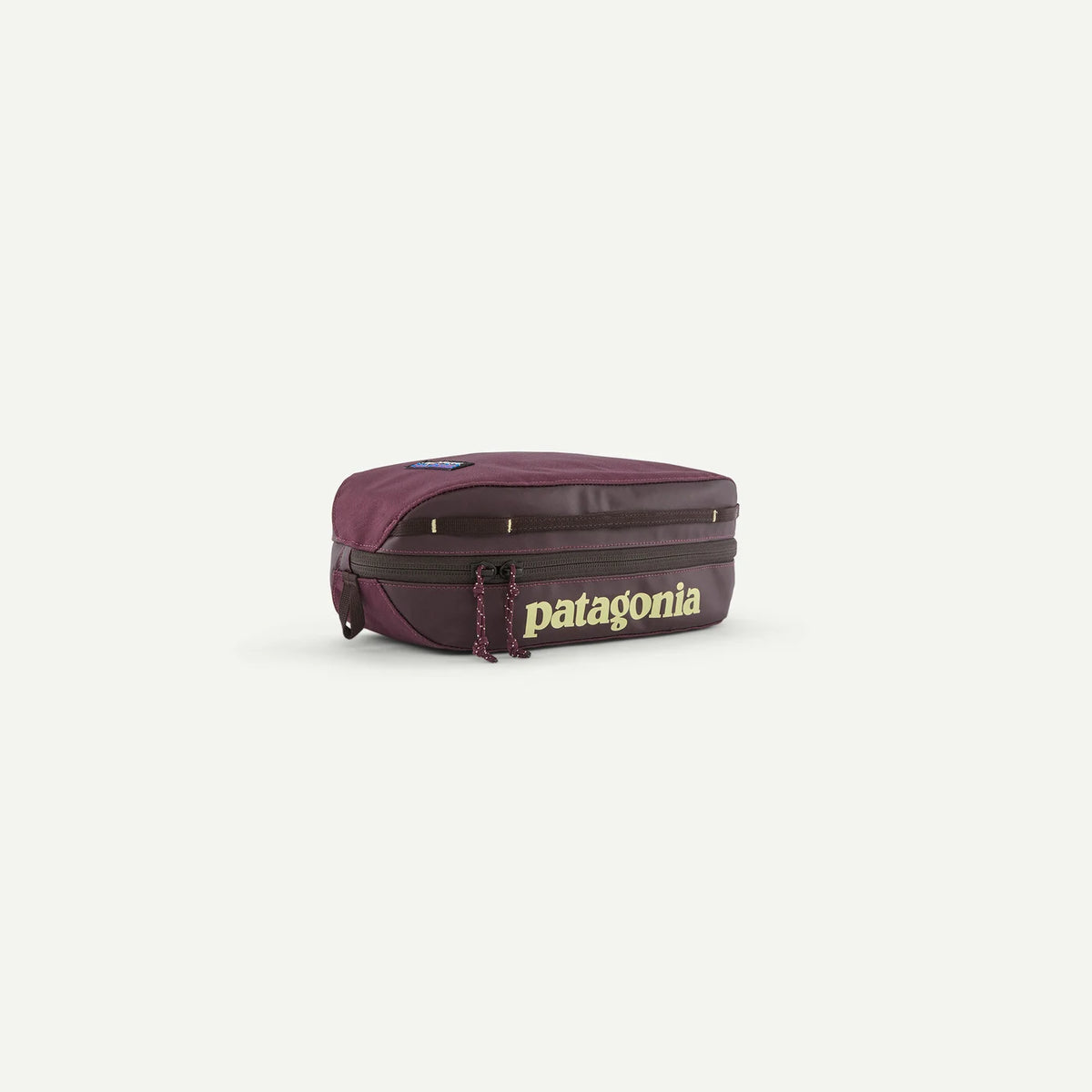 A Patagonia backpack in a deep plum purple color with dark brown trim and a prominent gold 'patagonia' logo on the front, set against a plain light gray background.