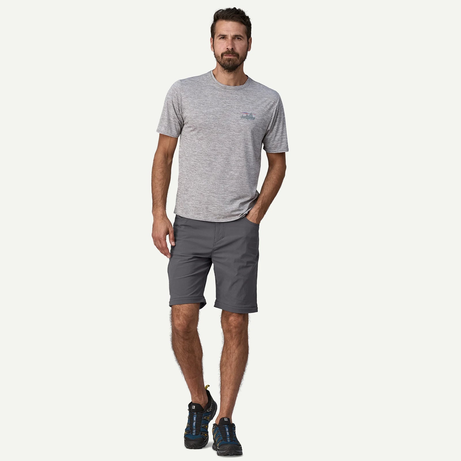 A man modeling a light gray heathered short-sleeve t-shirt and dark gray shorts against a solid off-white background.