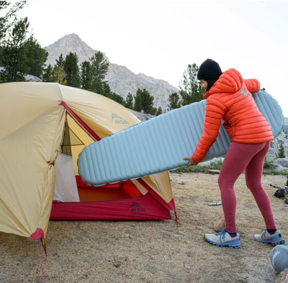 the neoair xtherm nxt sleeping pad shown being put into a tent by a model