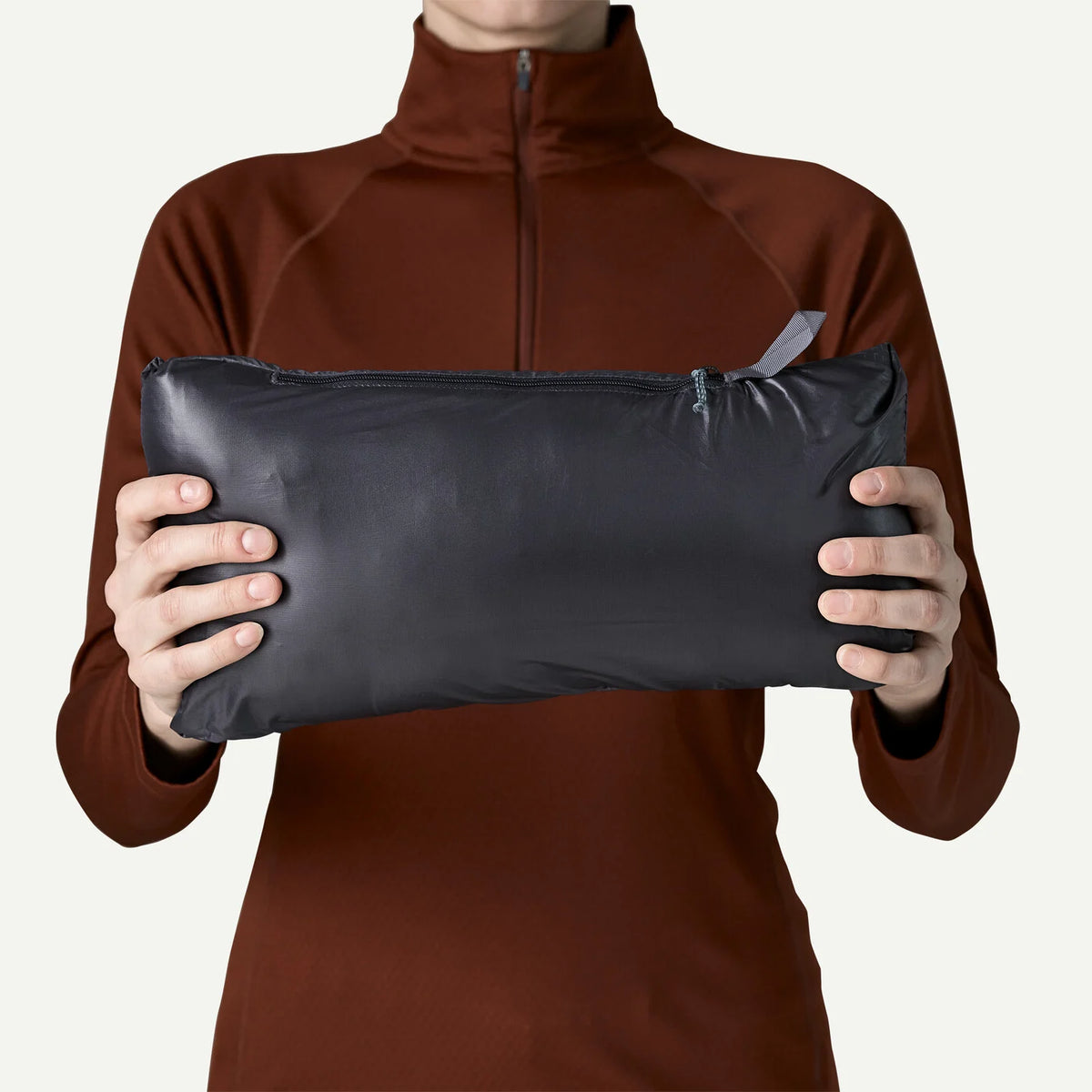 a person holding a dark blue-grey zippered pouch