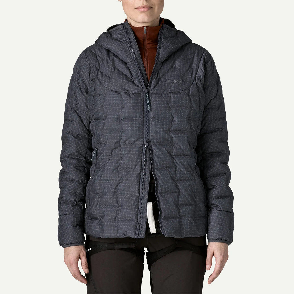 a person wearing a smolder blue down jacket with the zipper being half open from the bottom