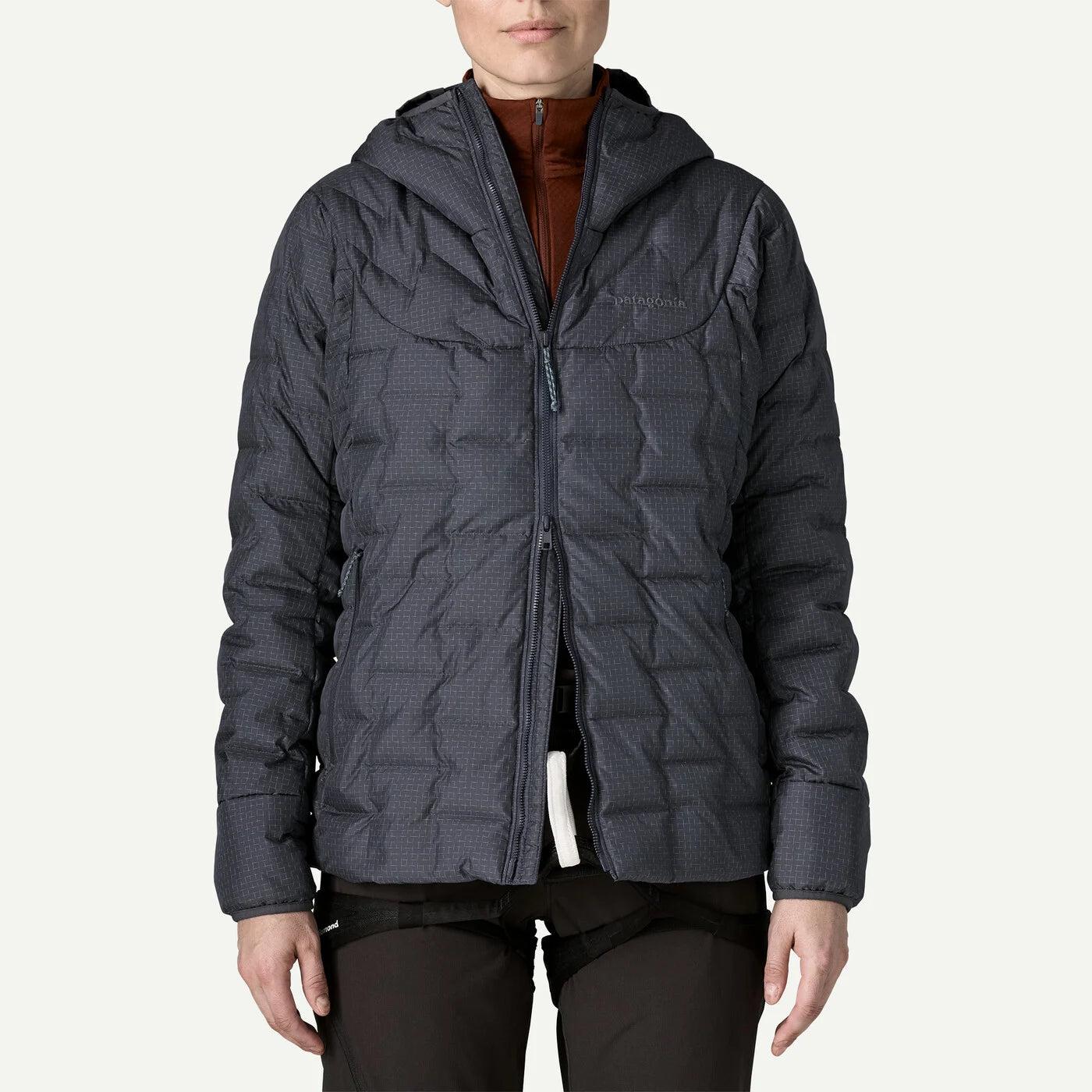 a person wearing a smolder blue down jacket with the zipper being half open from the bottom