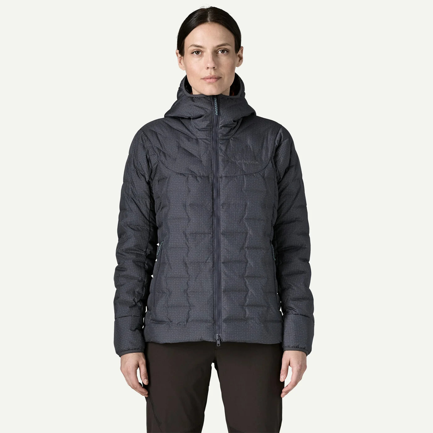 A woman modeling a dark gray hooded puffer jacket with a full-zip front, shown against a plain light gray background.