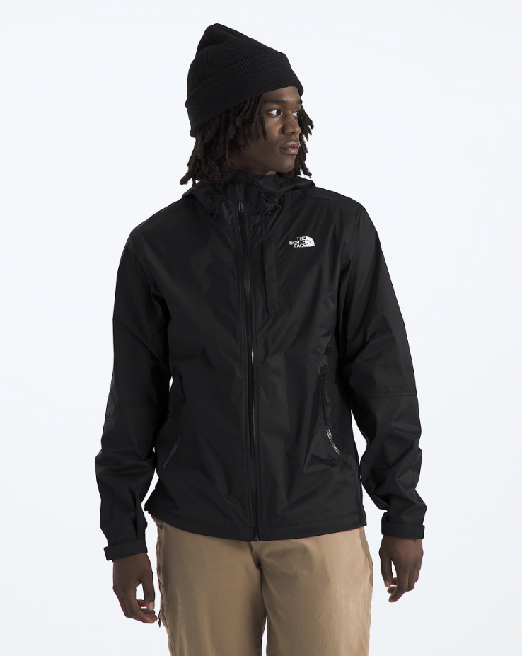 A man wearing a black The North Face hooded jacket, black beanie, and tan pants, photographed against a clean white studio background.
