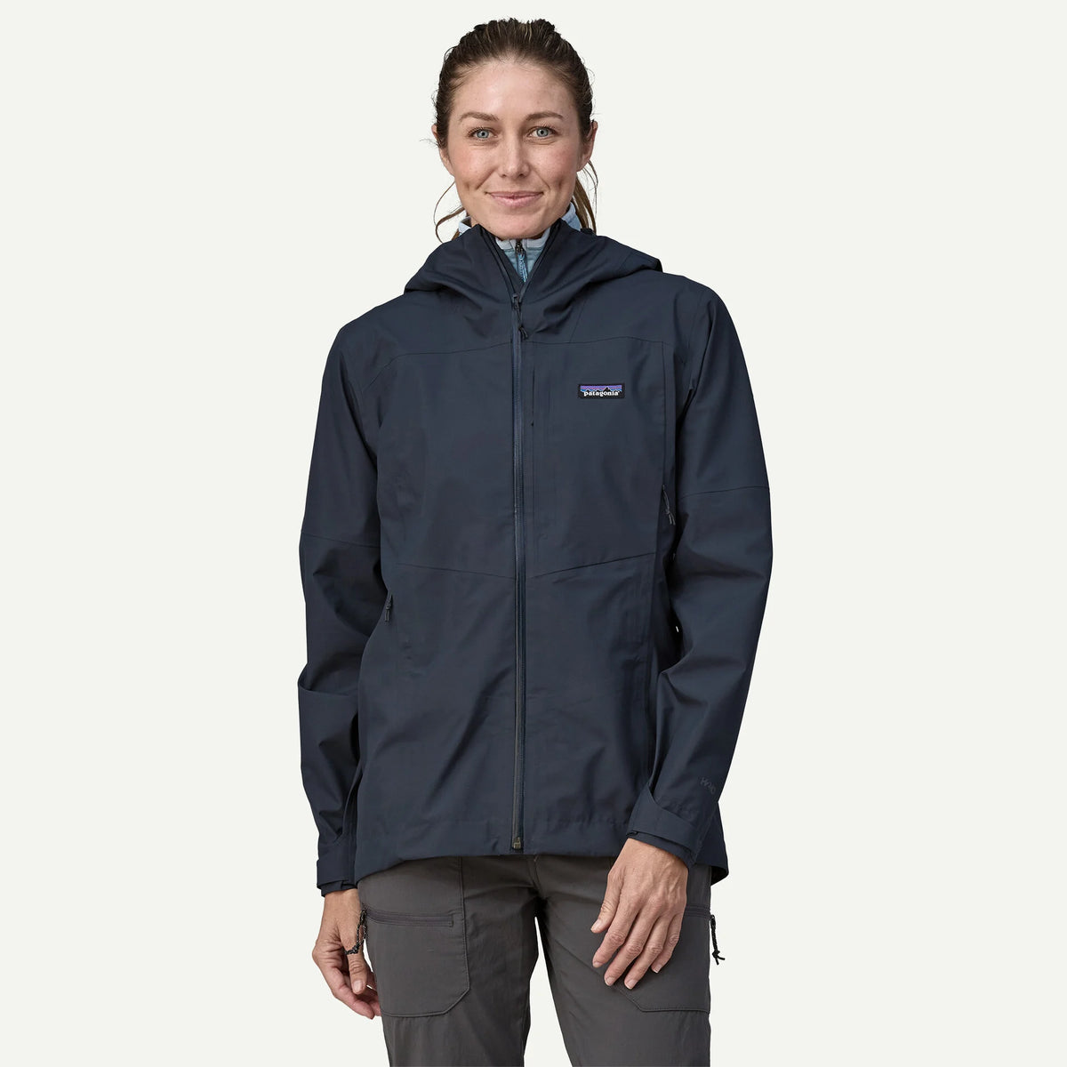 Person wearing a navy rain jacket with a visible brand logo on a white background