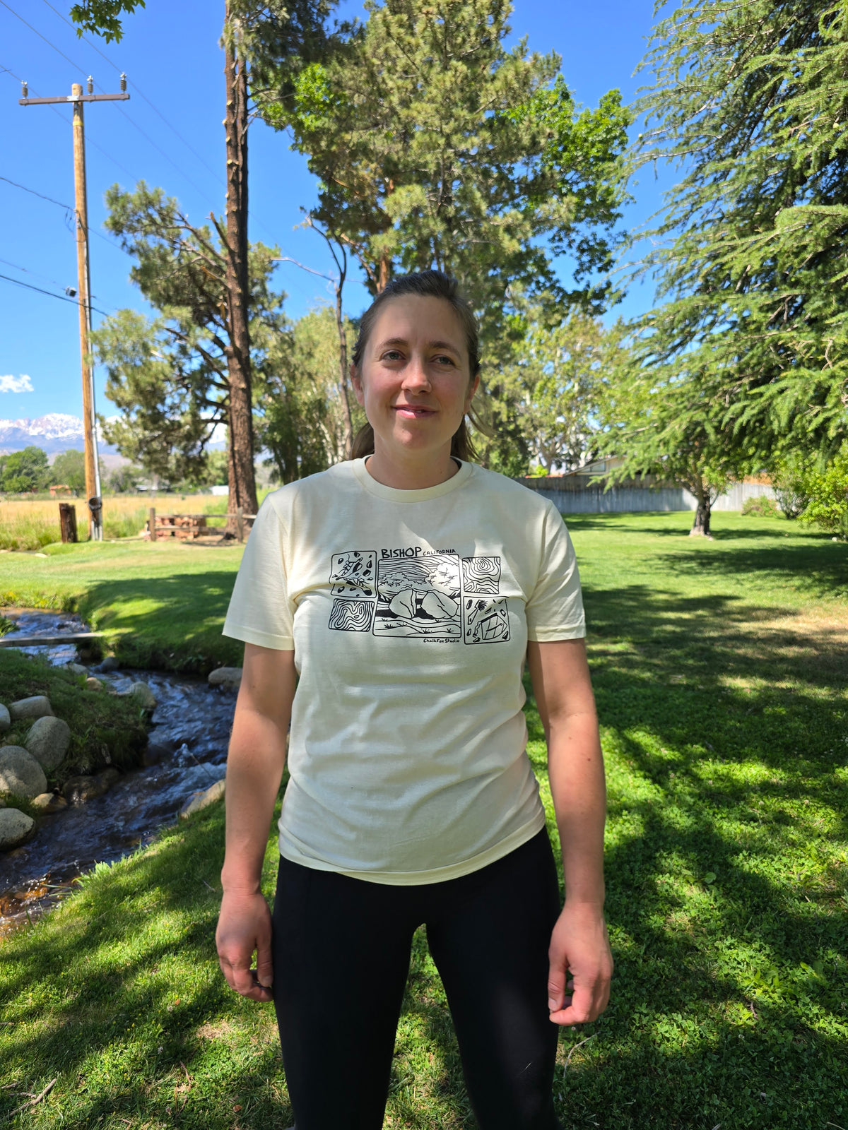 Person wearing a white t-shirt with graphics in a park setting