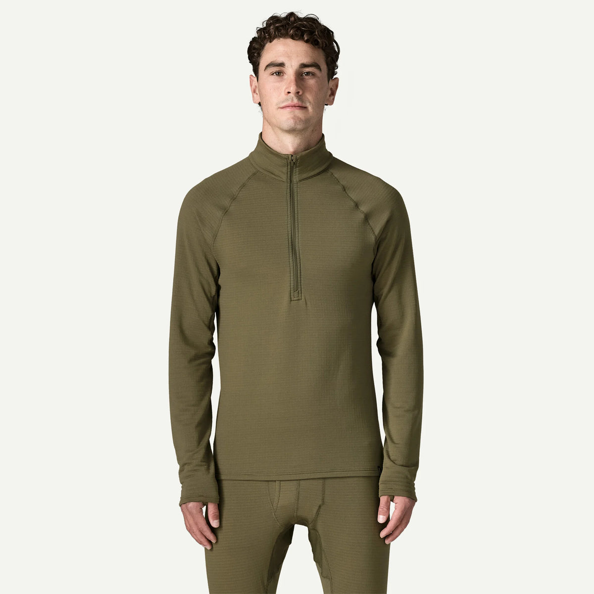 A man modeling a matching olive green long-sleeve quarter-zip performance top and matching pants against a light off-white background.
