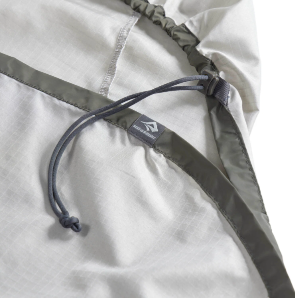 Close-up of a lightweight white hooded jacket or backpack with an olive green drawstring and a small gray brand tab