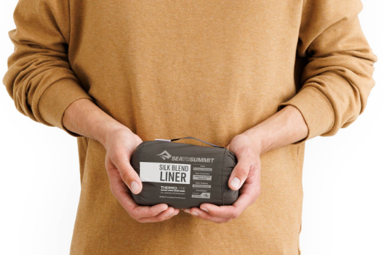 man holding sleeping bag liner in stuff sack