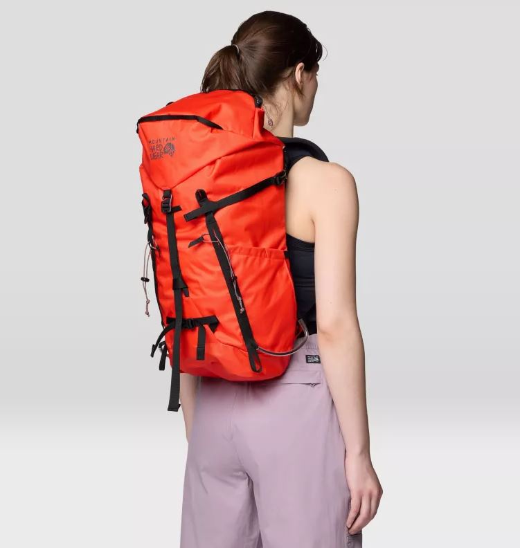 Mountain Hardwear Scrambler 25 Backpack, in state orange, worn by model, side view