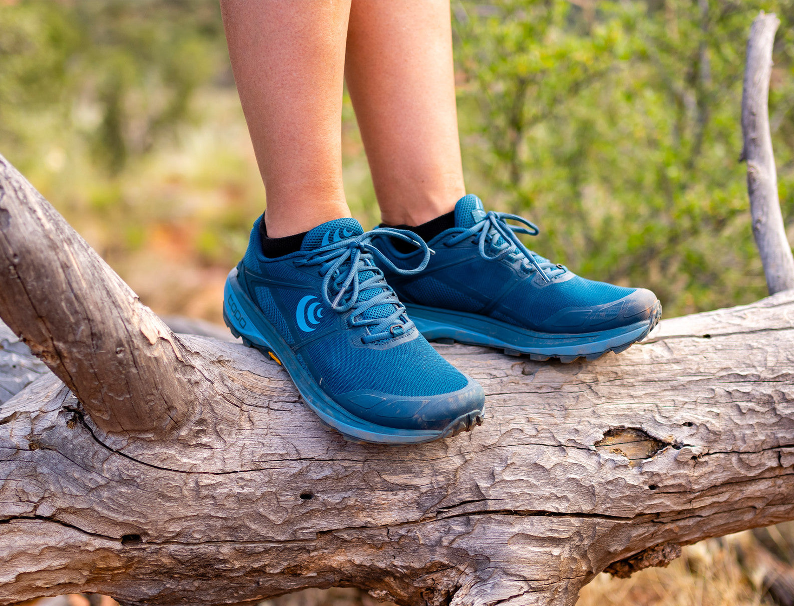a person wears the terraventure in blue while standing on a log