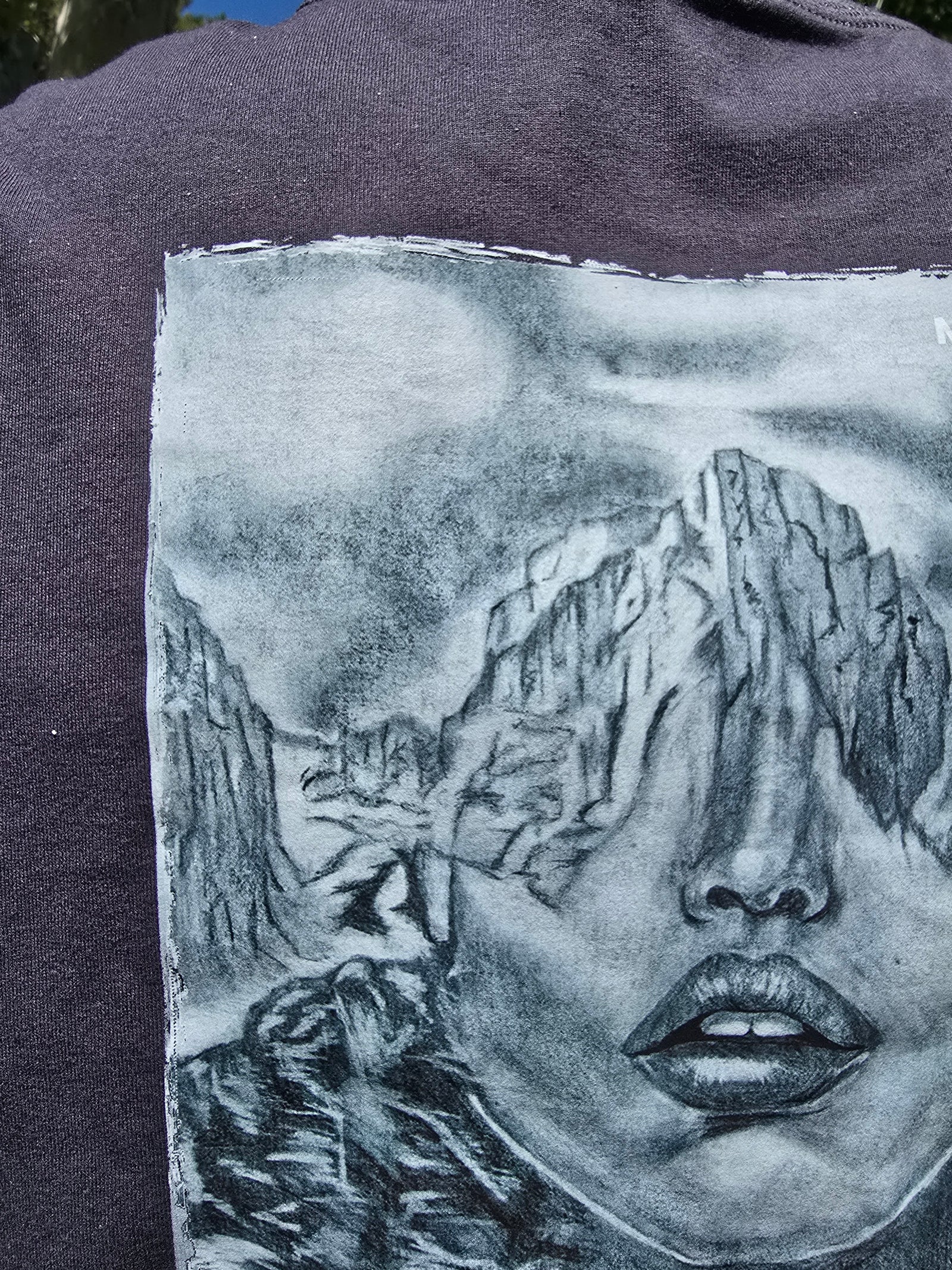 T-shirt with a graphic design of a face and mountains on a dark background