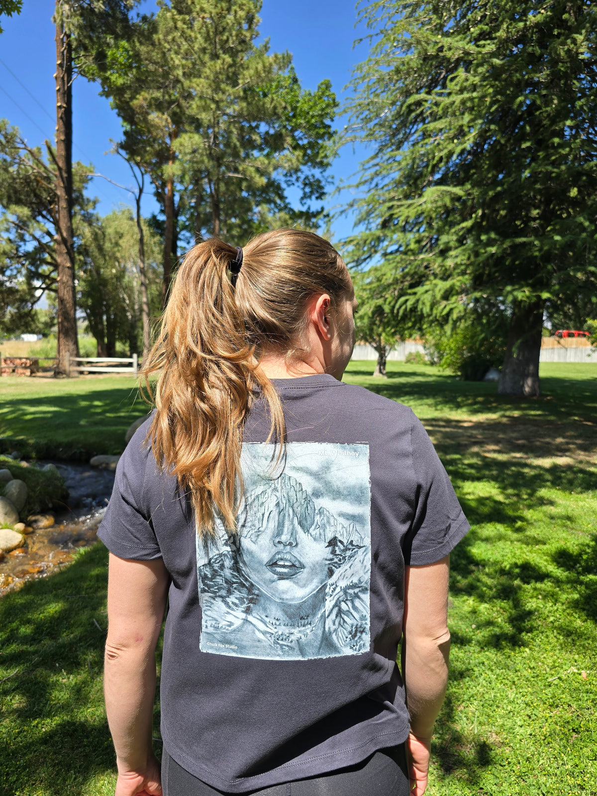 Person wearing a painting of a face outdoors with trees and grass in the background