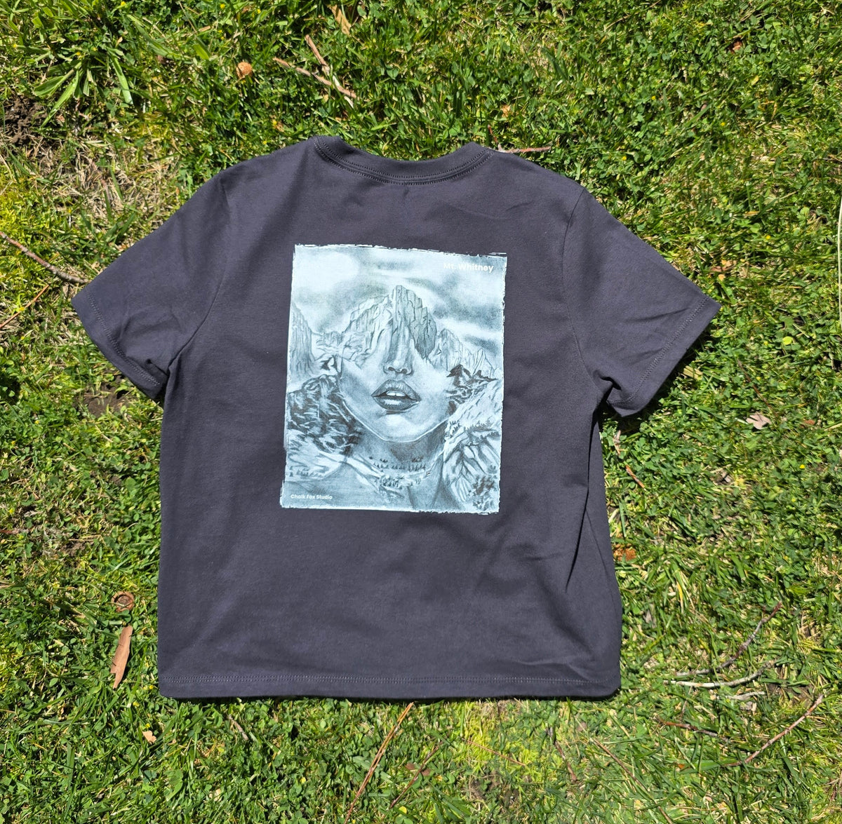 Black t-shirt with a graphic design on grass