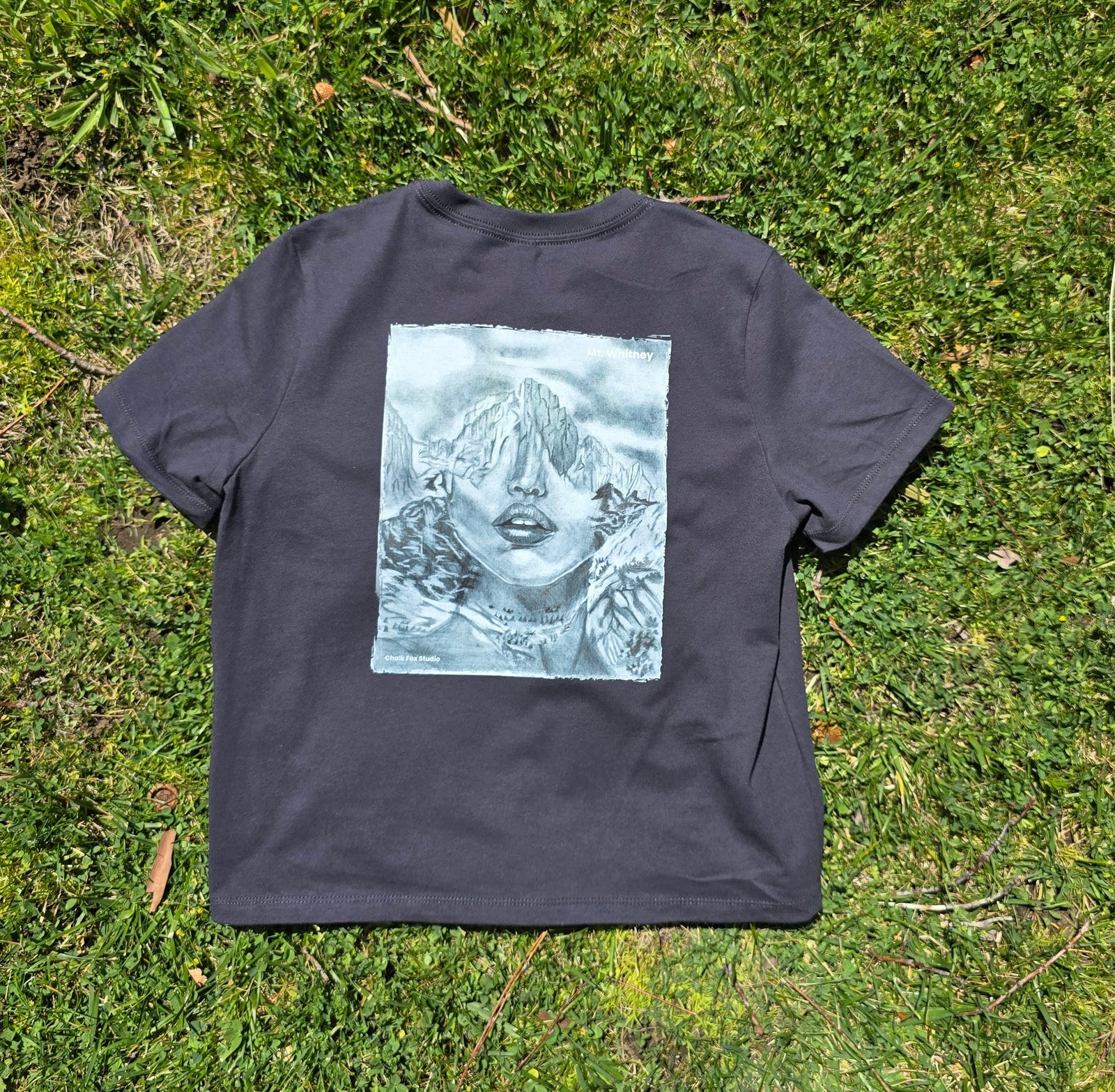 Black t-shirt with a graphic design on grass
