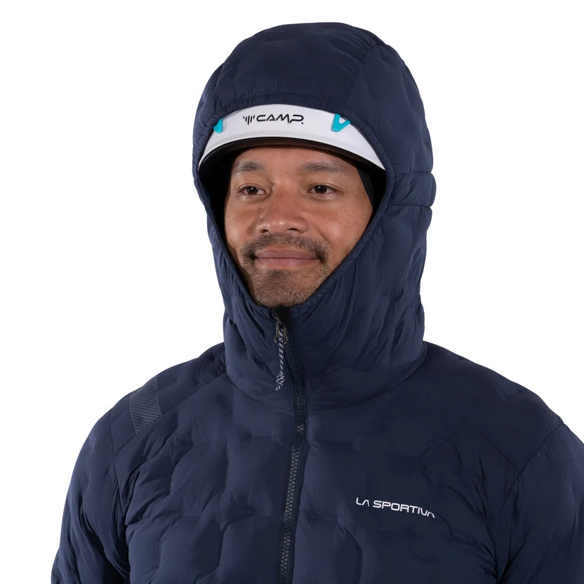 A man wearing a navy blue puffer jacket with a high hood and a white visor featuring the brand name 'CAMP'. The jacket has a white 'LA SPORTIV' logo on the left chest, set against a plain white background.