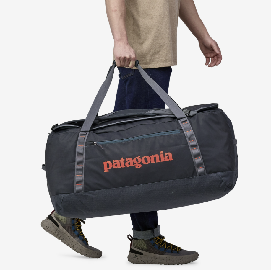 the patagonia black hole duffel in color smolder blue, being held by a model