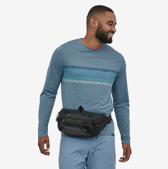 the patagonia black hole waist pack in the color black, front view on a model