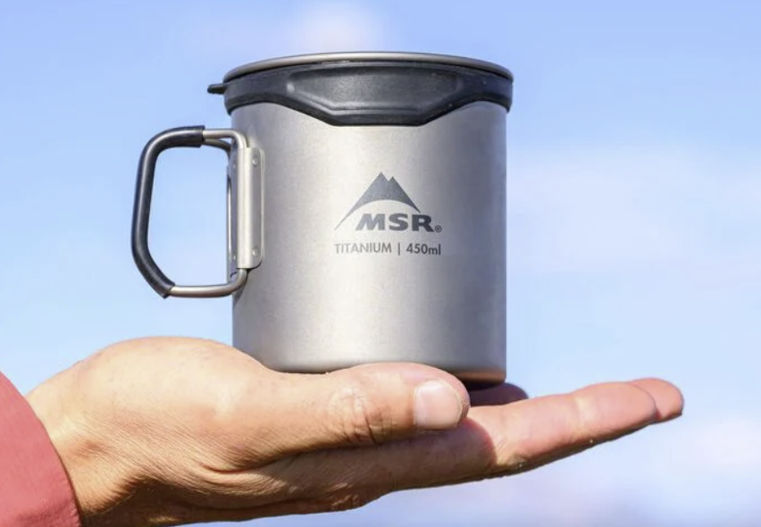 a photo of a hand holding the msr titan cup