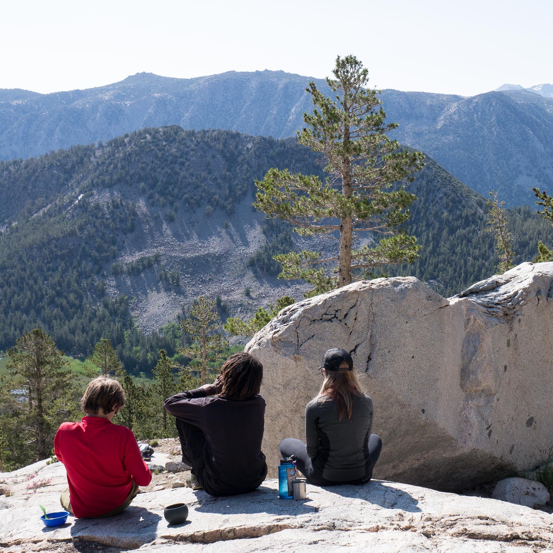 kids sitting on a rock slab enjoying a view of mountains